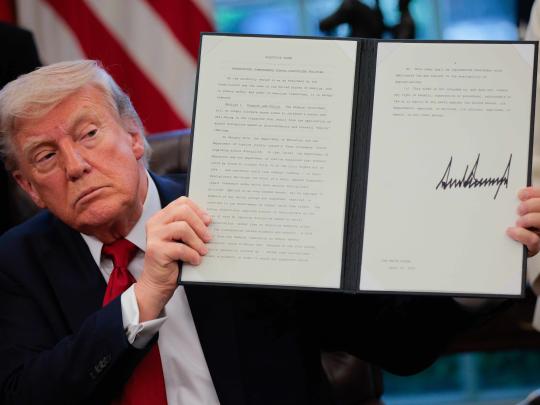 Donald Trump holding up a signed executive order
